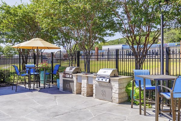 Outdoor grill area at Clear Creek Meadows Apartments featuring modern BBQ stations and seating in a tranquil setting