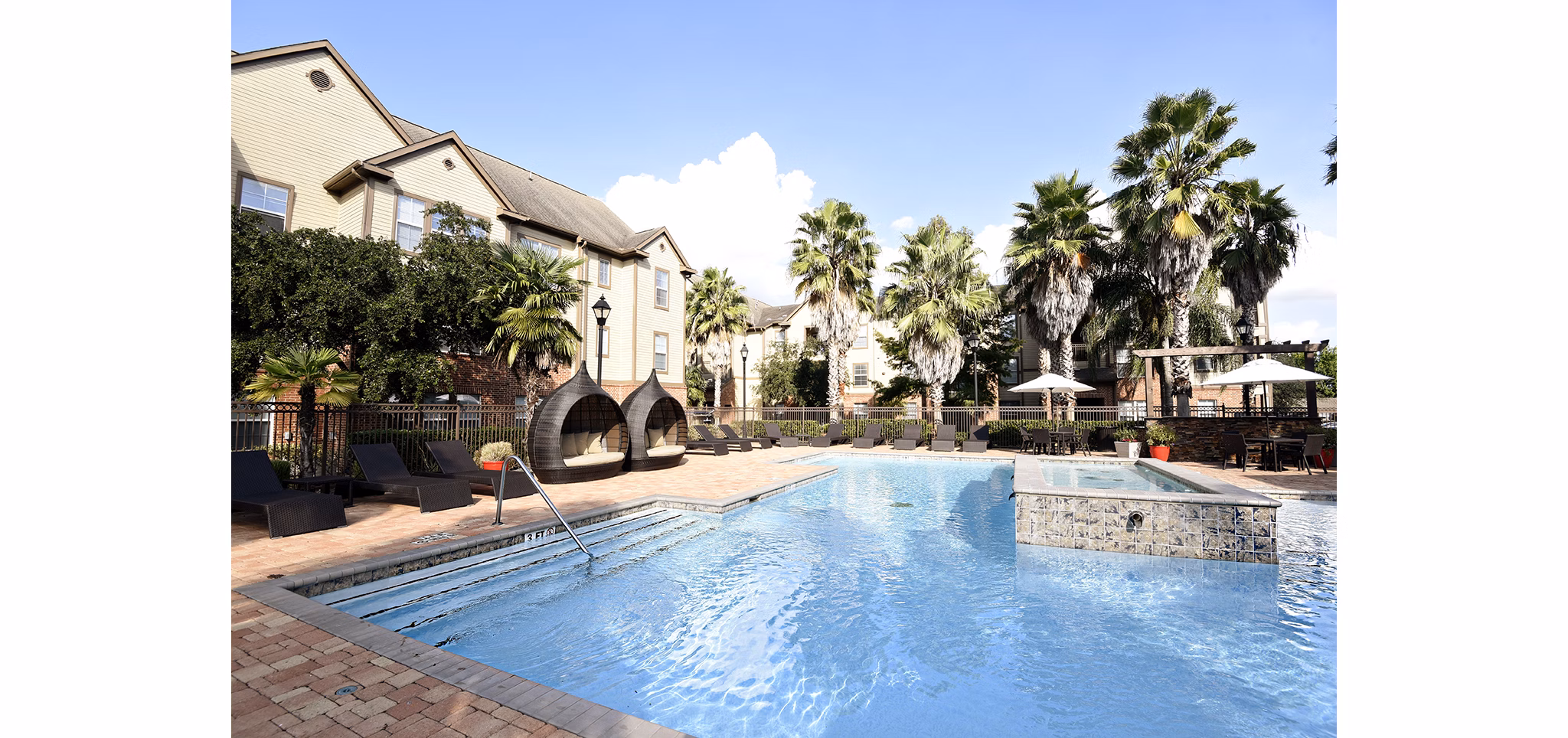 Resort-style pool at Avana Sugar Land Apartments with sun loungers and landscaped surroundings
