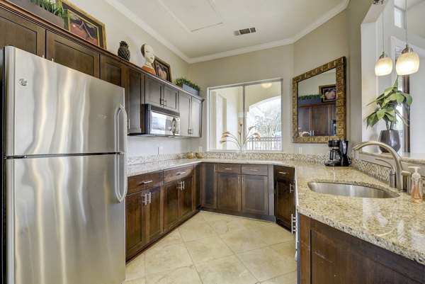 Modern kitchen with stainless steel appliances and granite countertops at Terrazzo Apartments luxury living by Greystar