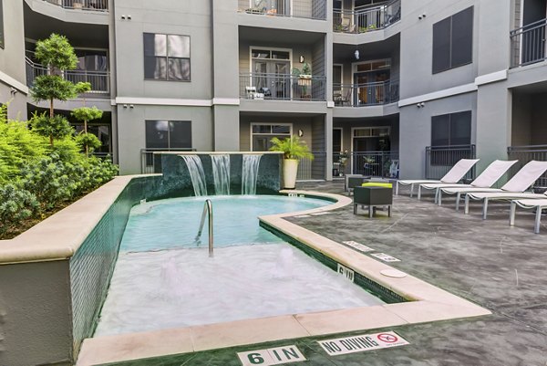 Resort-style pool with lounge chairs at The Westheimer Apartments, offering a relaxing luxury living experience in the heart of Houston