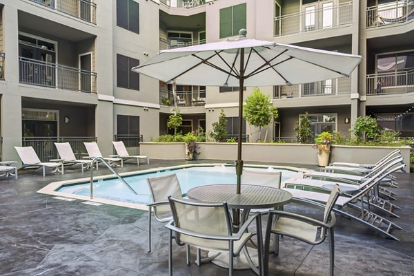 Luxurious pool at The Westheimer Apartments featuring modern lounge chairs and lush landscaping, ideal for relaxation and leisure activities