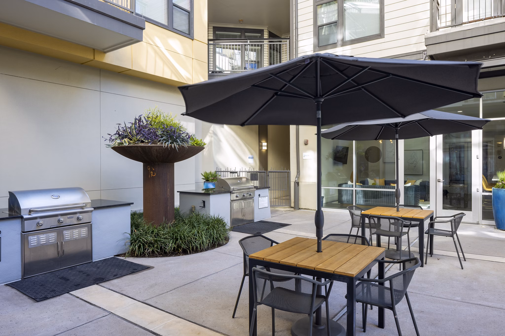 Grill area with modern seating and lush landscaping at Haus 5350 Apartments, perfect for social gatherings in a luxury setting