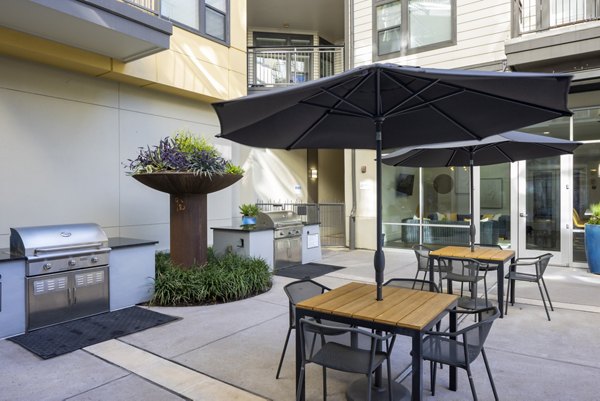 Grill area with modern seating and lush landscaping at Haus 5350 Apartments, perfect for social gatherings in a luxury setting