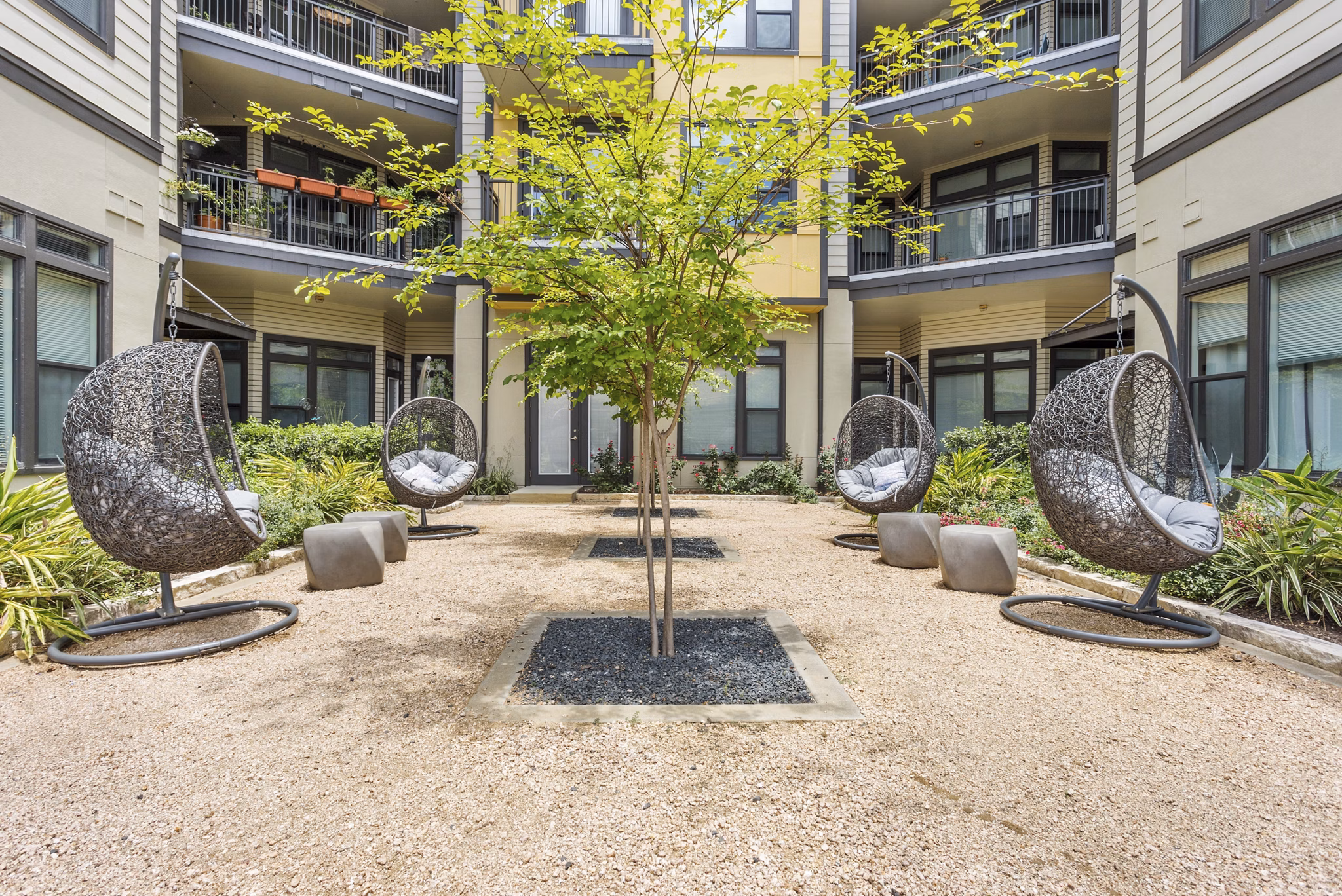 Charming courtyard with lush greenery at Milano Apartments, offering a serene outdoor space for relaxation and leisure