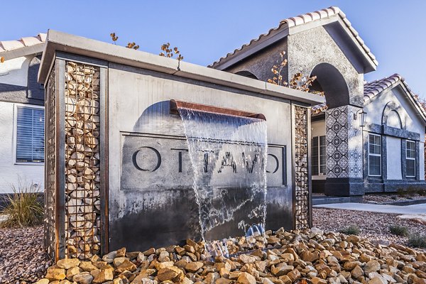 Decorative water feature with Ottavo surrounded by rocks in front of an arched building with a tiled roof