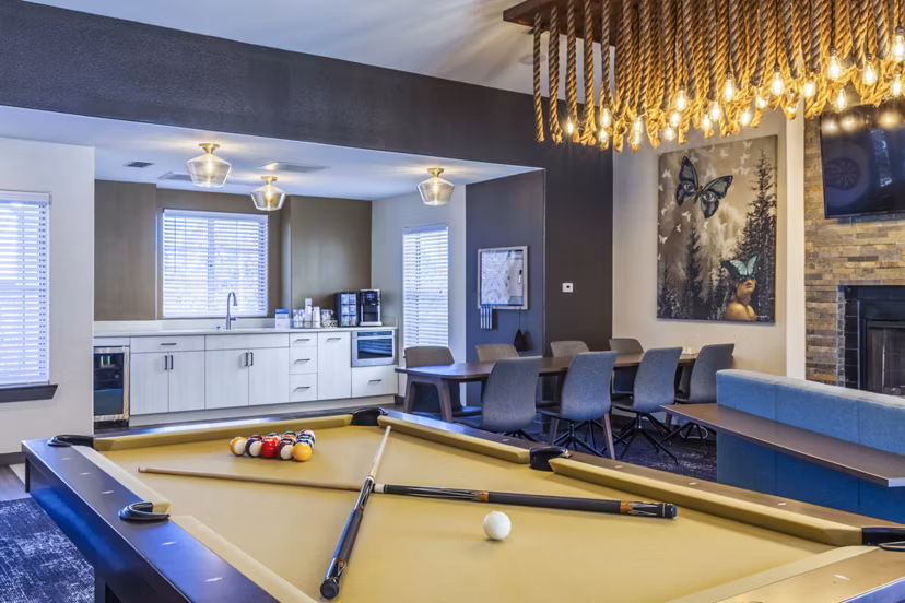 Clubhouse game room with pool table and lounge seating in OTTAVO Apartments offering luxury living