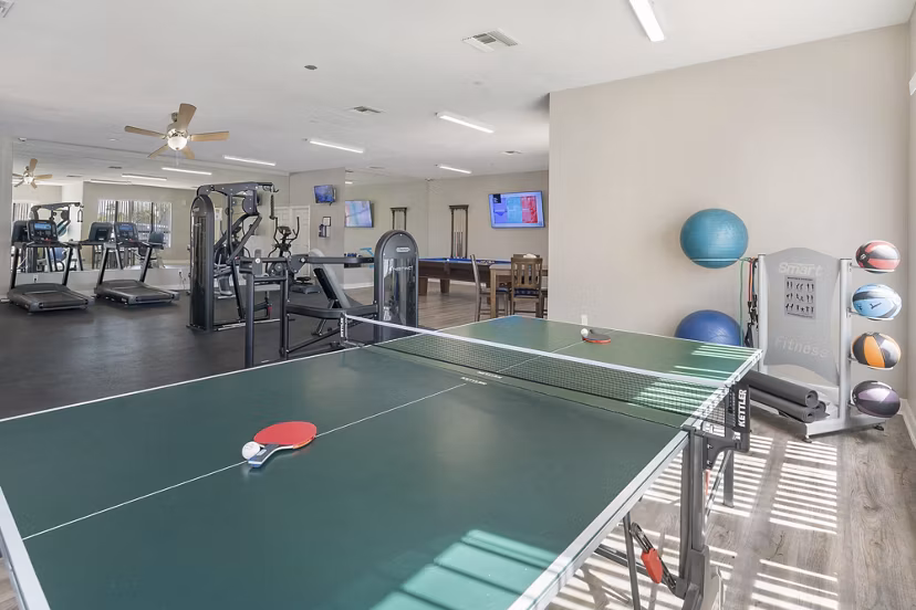 Modern fitness center and clubhouse game room at The Colony Apartments offering luxury amenities