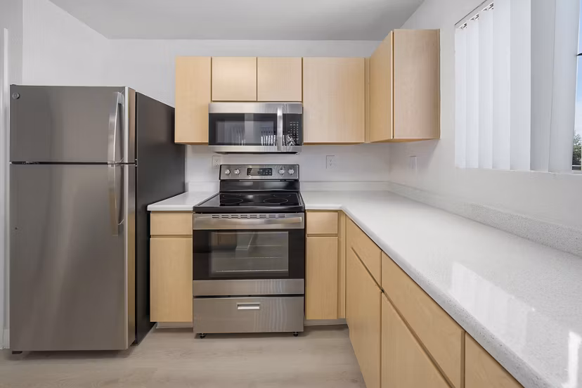 Modern kitchen with stainless steel appliances and marble countertops in The Colony Apartments