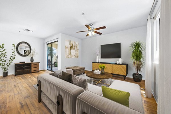 Cozy living room with modern furnishings and large windows at The Colony Apartments