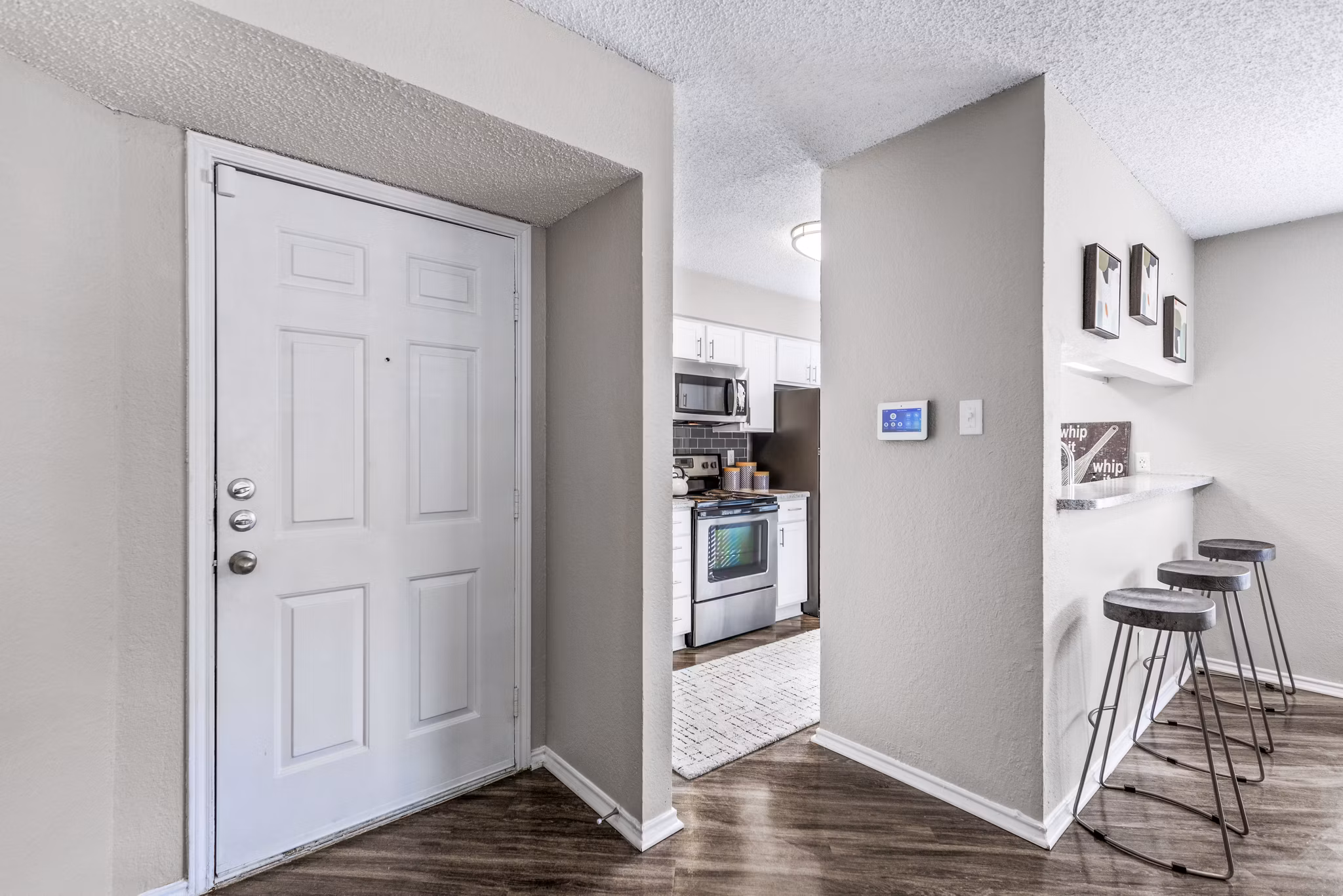 Entrance leading to a modern kitchen at The Georgian Apartments featuring sleek cabinetry and stainless steel appliances