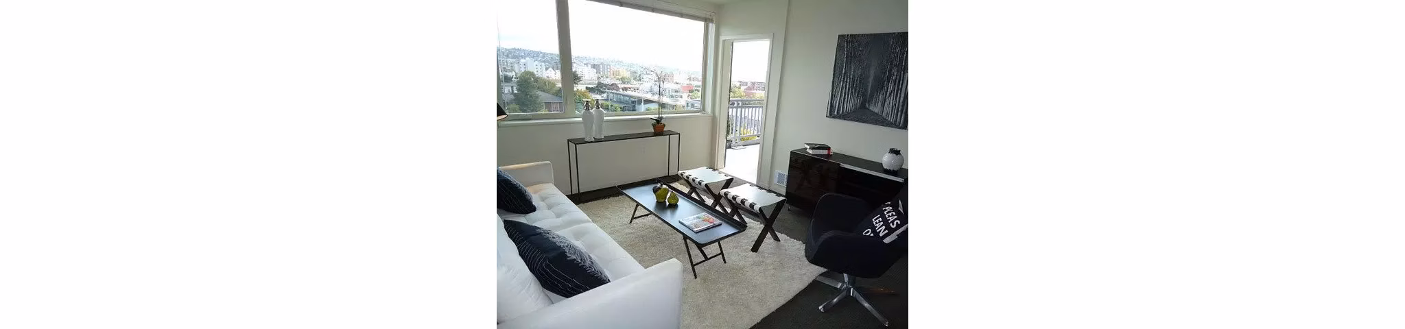 Spacious living room with modern furniture and large windows at On the Park Apartments