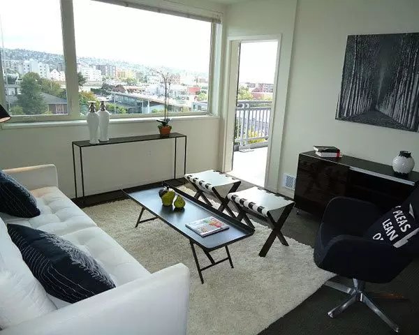 Spacious living room with modern furniture and large windows at On the Park Apartments