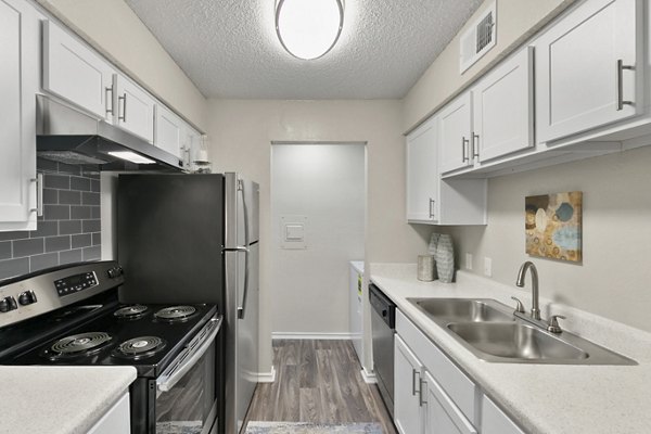 Kitchen featuring modern appliances and granite countertops at Creekwood Apartments