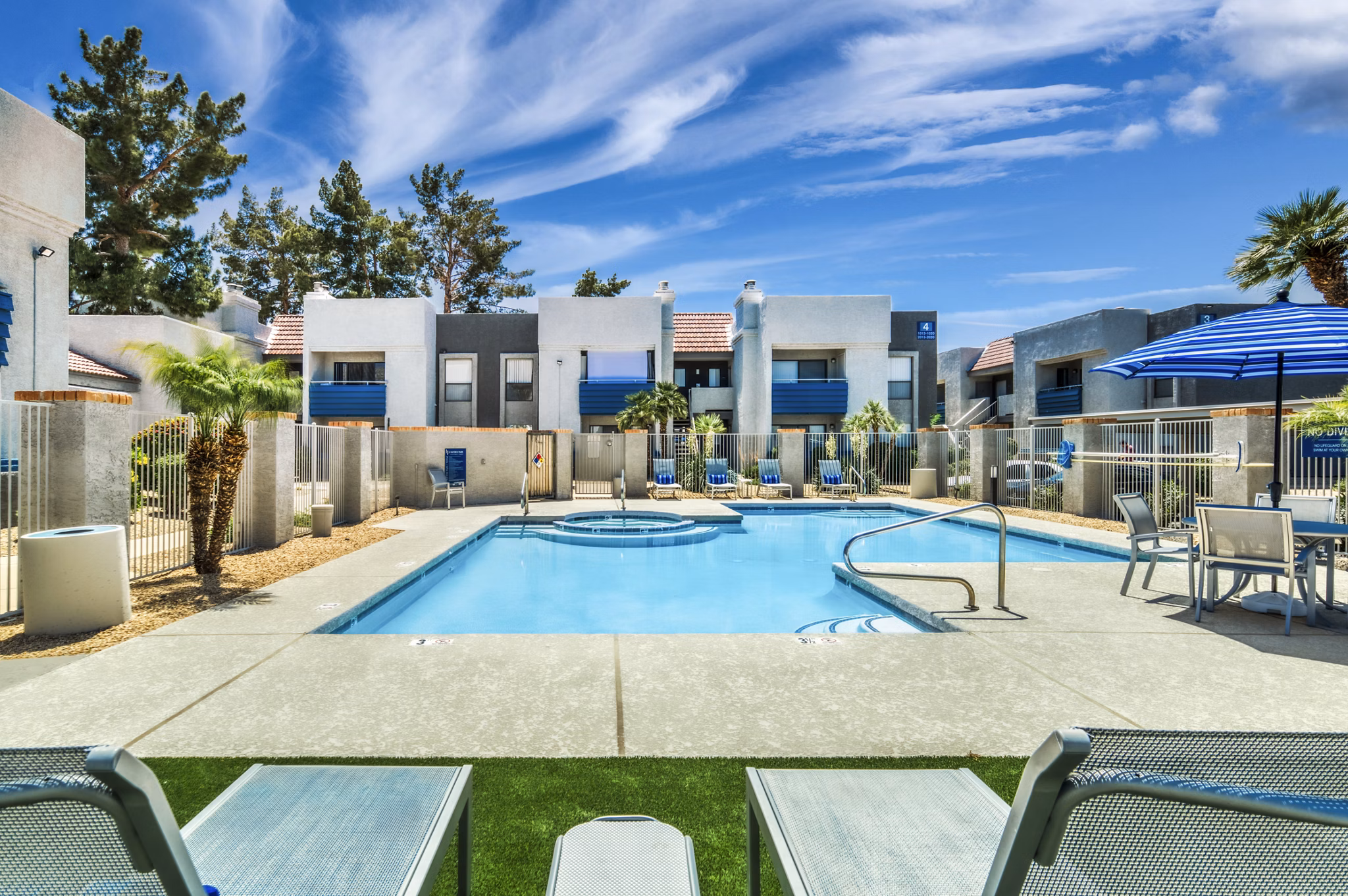 Resort-style outdoor pool at Hayden Park Apartments featuring sun loungers and lush landscaping, perfect for relaxation and socializing
