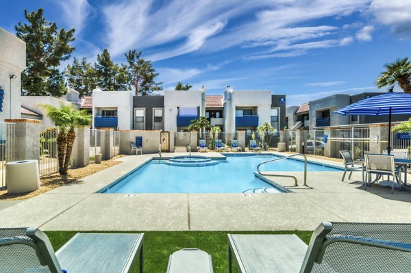 Resort-style outdoor pool at Hayden Park Apartments featuring sun loungers and lush landscaping, perfect for relaxation and socializing