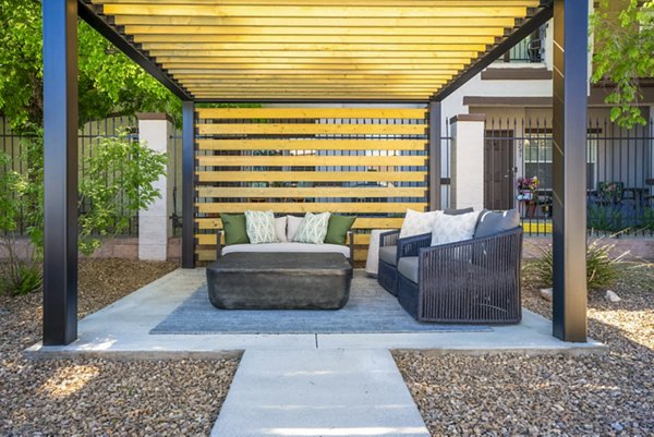 Modern outdoor patio at Cantata at the Trails Apartments featuring cozy seating and lush greenery