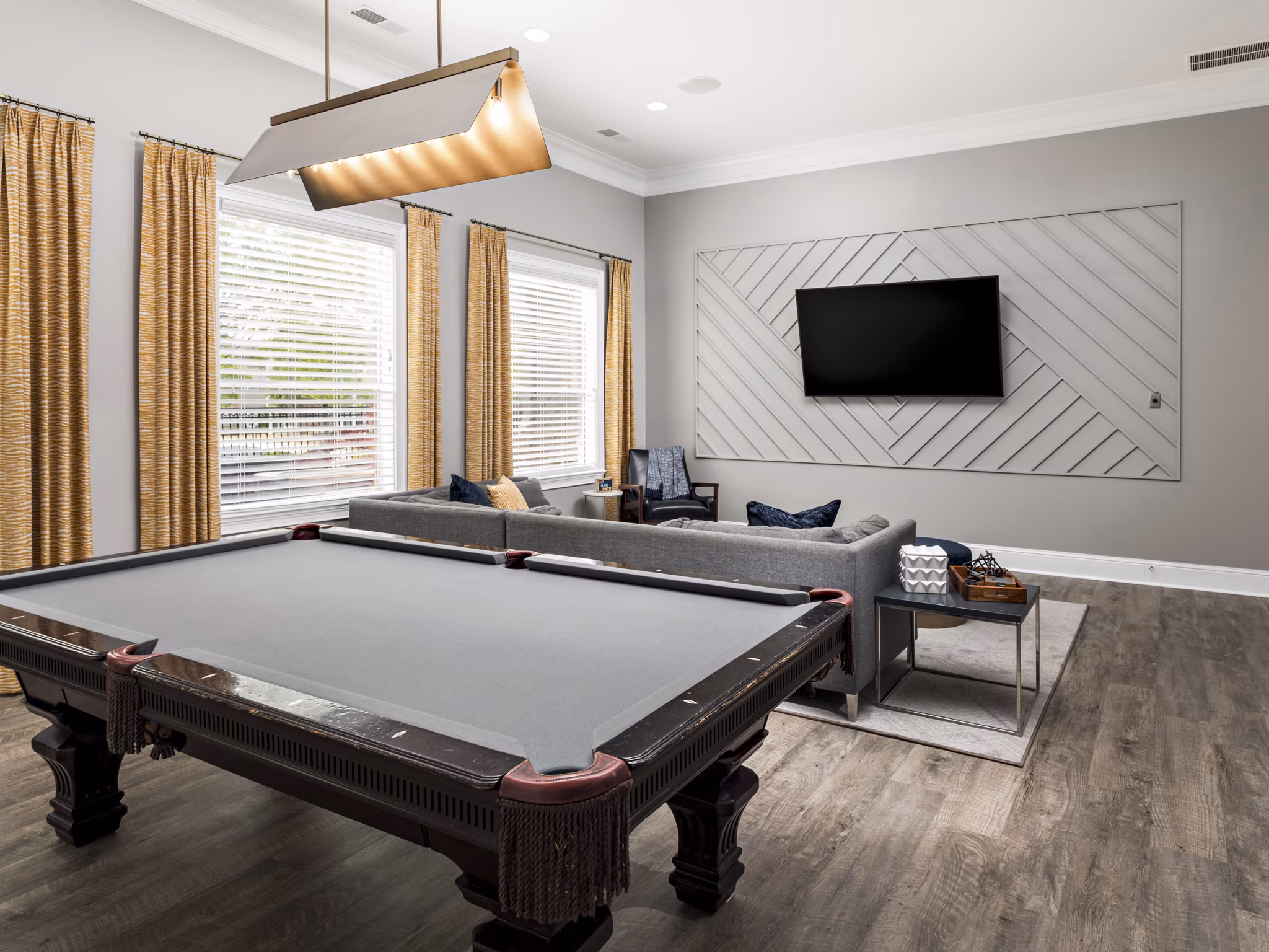 Clubhouse game room with pool table and large-screen TV at Mandalay Villas Apartments