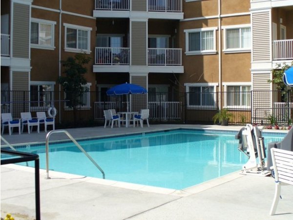 Resort-style pool at Raincross Senior Village Apartments with surrounding lounge chairs