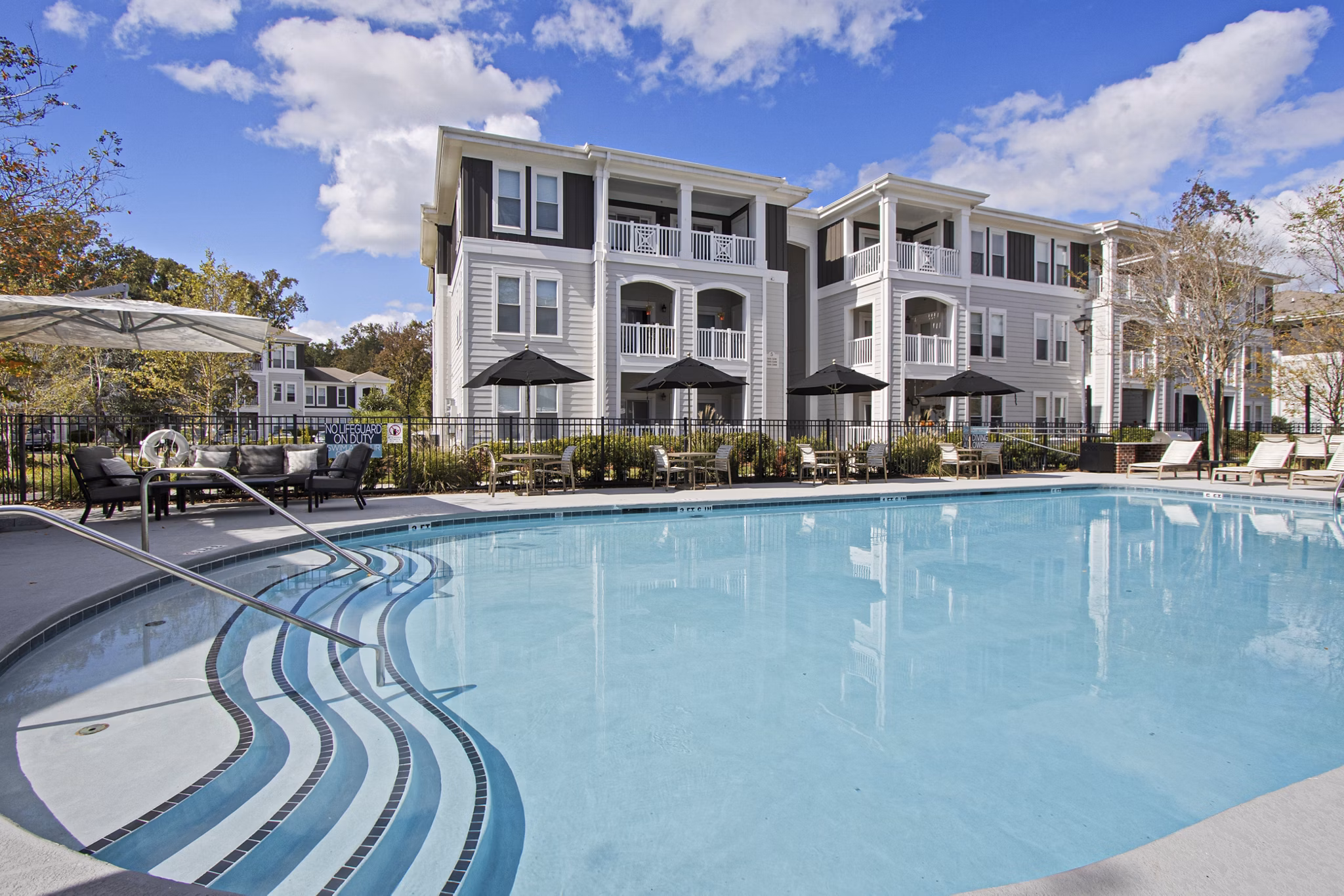 Luxurious pool at 1000 West Apartments with lounge chairs and greenery