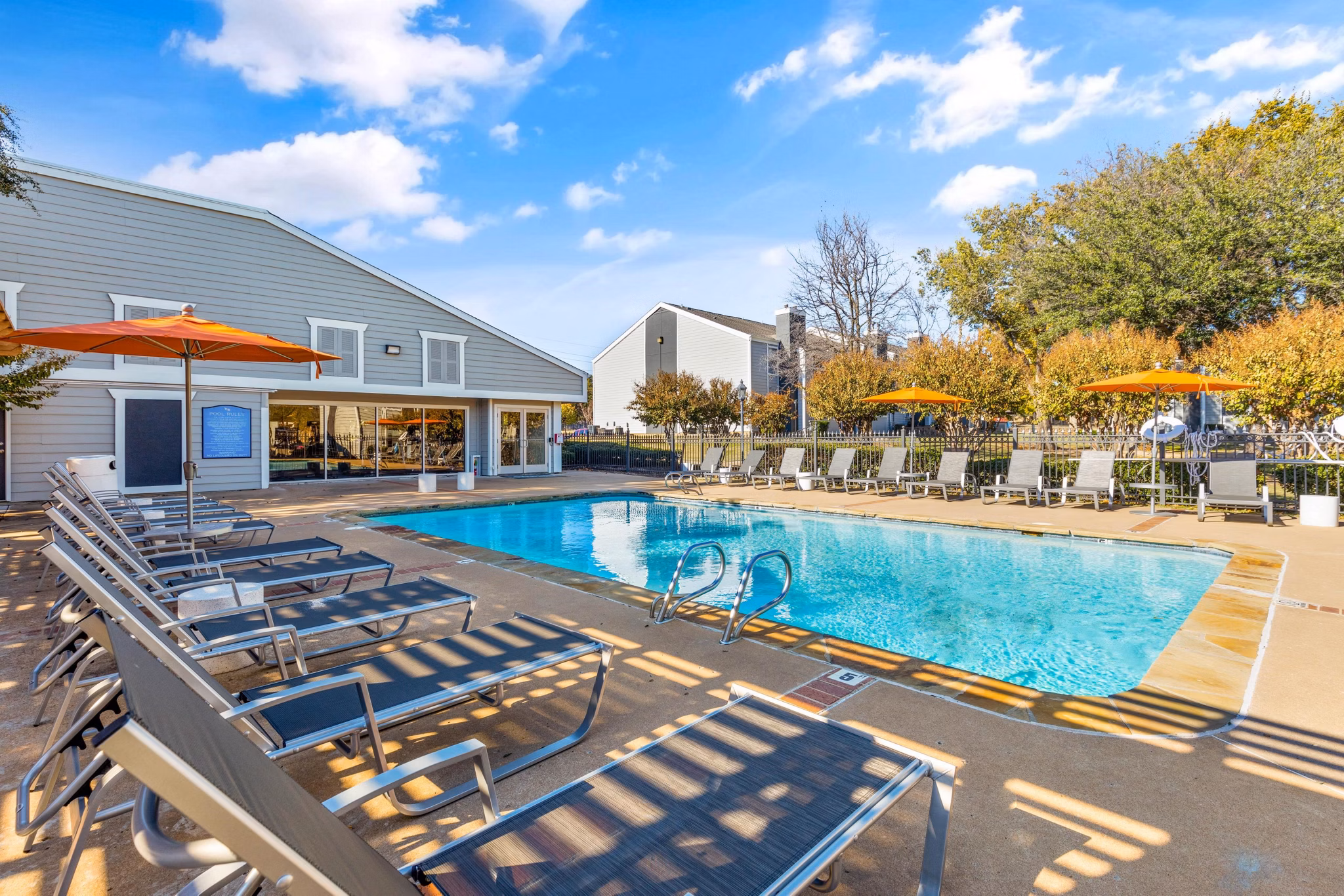 Outdoor pool surrounded by sun loungers at Coventry Park Apartments offering a luxurious and relaxing atmosphere for residents