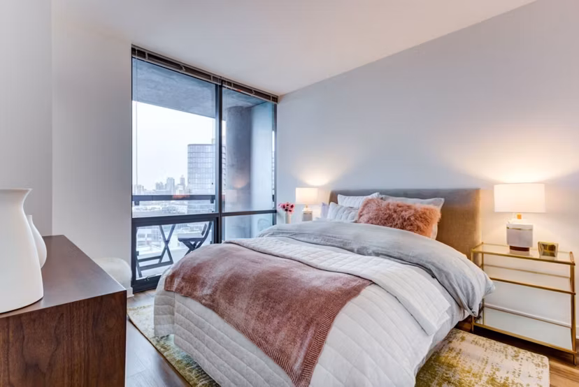Modern bedroom featuring cozy decor and large windows at SoNo East Apartments