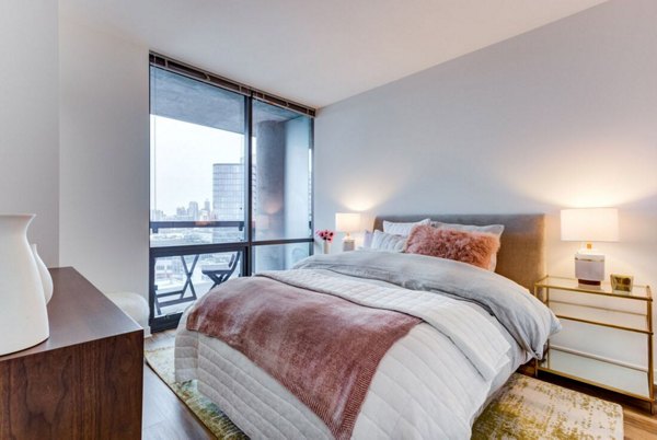 Modern bedroom featuring cozy decor and large windows at SoNo East Apartments