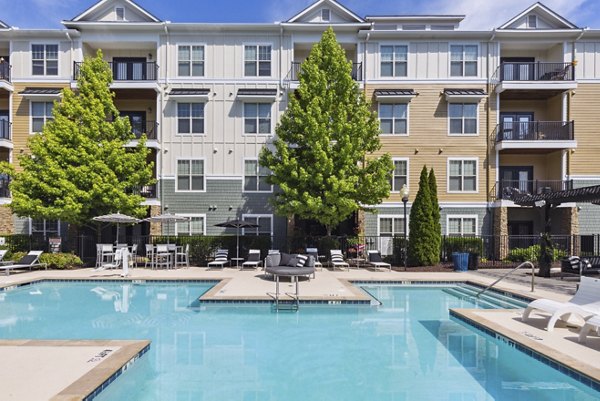 Relaxing poolside scene at Verde Vista Apartments with luxury sun loungers and greenery