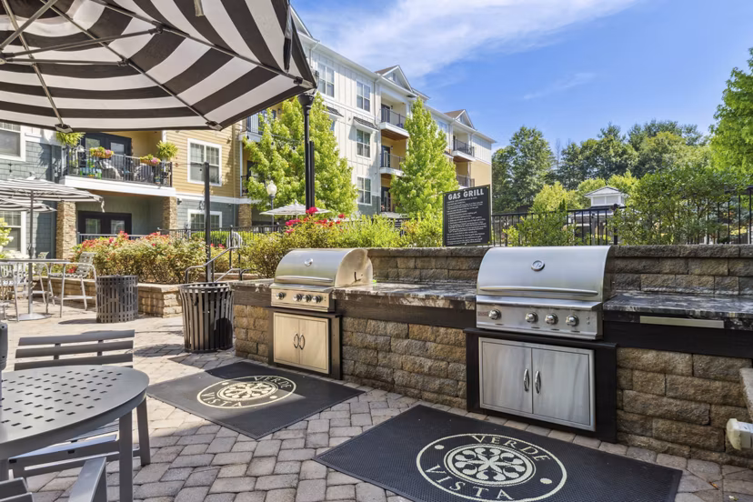 Outdoor grill area at Verde Vista Apartments with modern seating and lush landscaping