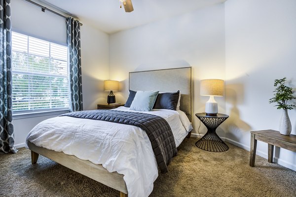 Bedroom with modern decor and large windows in The Vinoy at Innovation Park Apartments