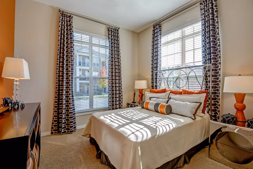 Spacious bedroom with modern decor at Whitehall Parc Apartment Homes, featuring large windows and neutral tones for a relaxing ambiance