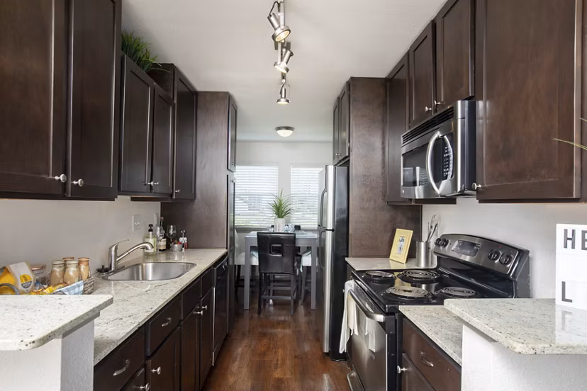 Modern kitchen with granite countertops and stainless steel appliances in Reserve at Garden Oaks Apartments