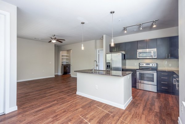 Modern kitchen with sleek appliances and granite countertops at Tree Apartments