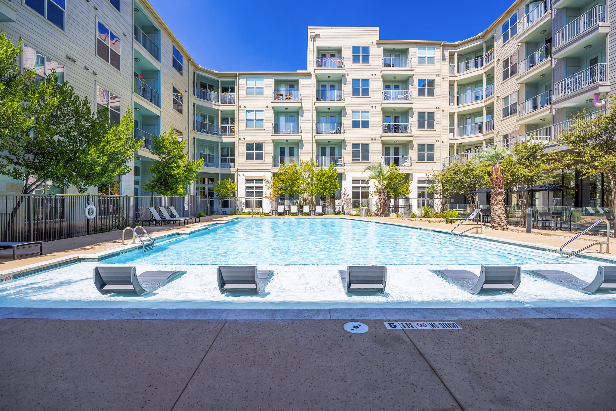 Inviting outdoor pool surrounded by lush landscaping at Tree Apartments, luxury living by Greystar