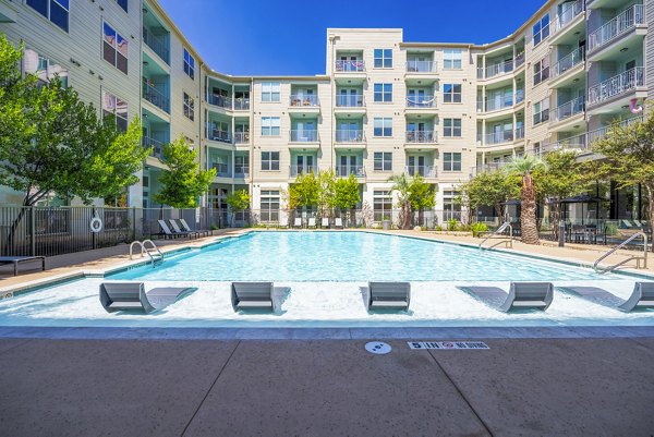 Inviting outdoor pool surrounded by lush landscaping at Tree Apartments, luxury living by Greystar