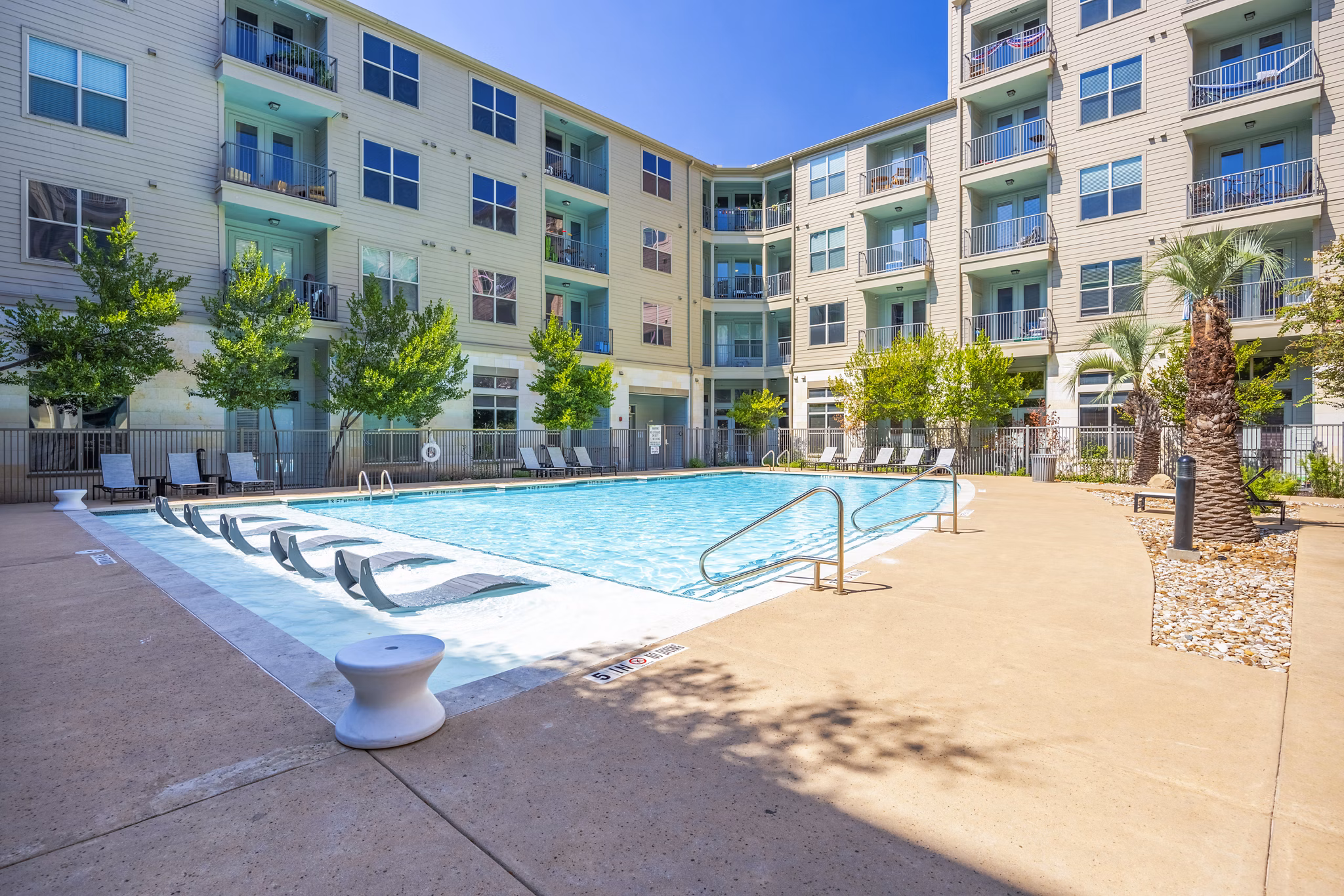 Resort-style outdoor pool with sun loungers at Tree Apartments, a luxury Greystar community