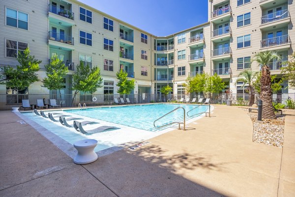 Resort-style outdoor pool with sun loungers at Tree Apartments, a luxury Greystar community