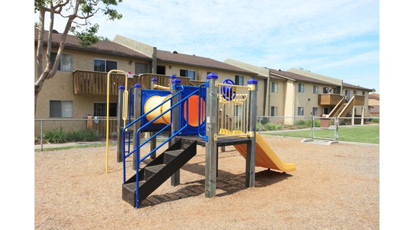Playground with colorful equipment at Ocean Breeze Apartments, perfect for family fun and relaxation in a vibrant community setting