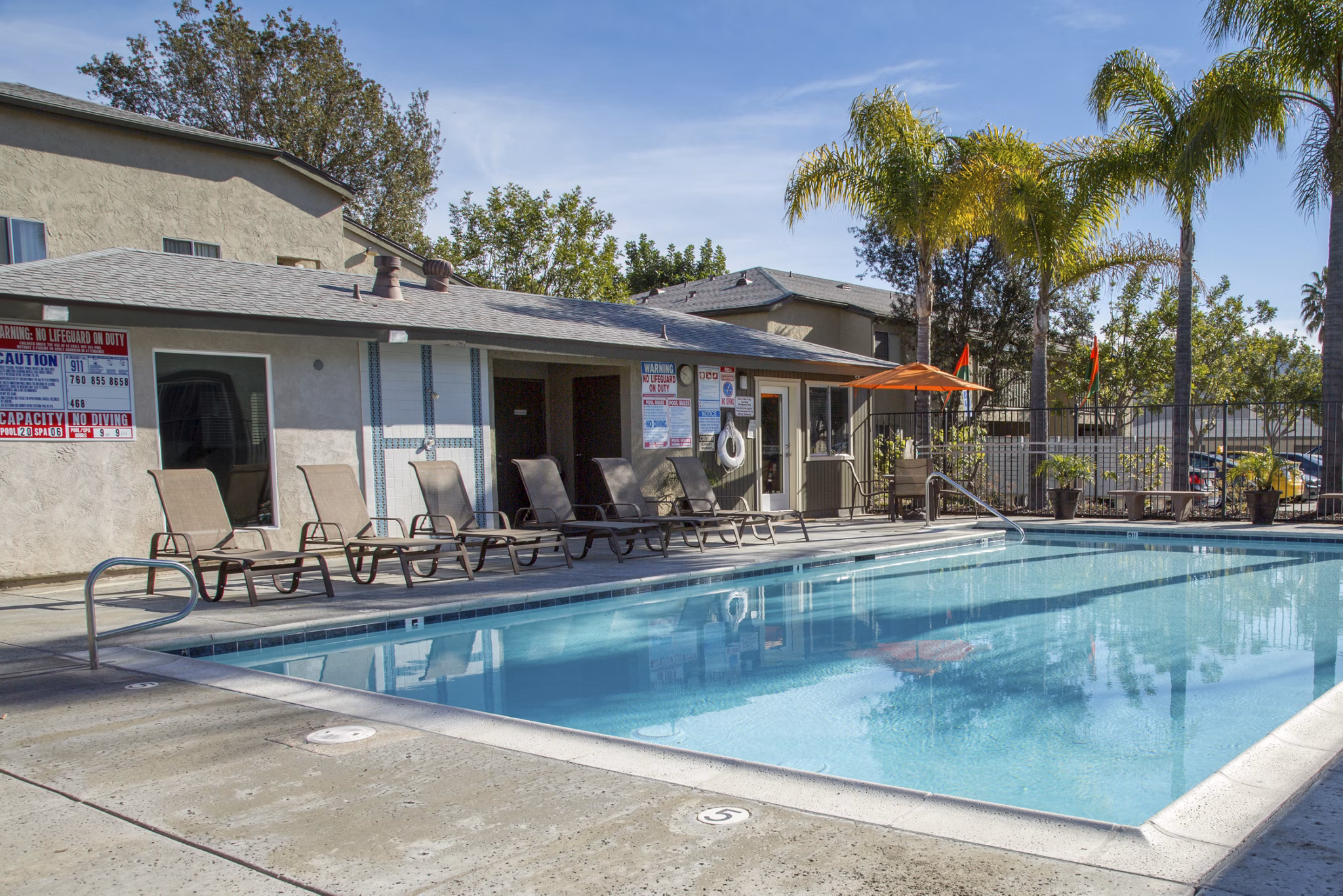 Inviting pool area at Whispering Oaks Apartments, featuring luxurious poolside lounge chairs and lush landscaping for relaxation and leisure