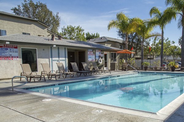 Inviting pool area at Whispering Oaks Apartments, featuring luxurious poolside lounge chairs and lush landscaping for relaxation and leisure