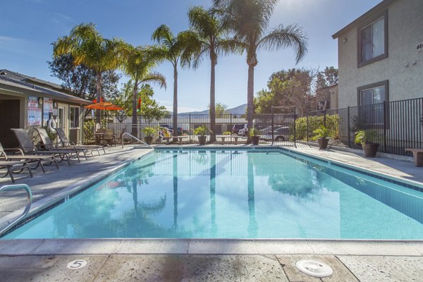 Pool area with lounge chairs and landscaped surroundings at Whispering Oaks Apartments, a luxury Greystar community