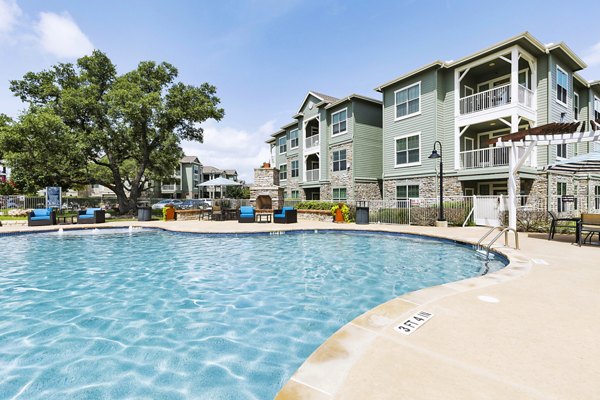 Outdoor pool at 95Twenty Apartments, featuring sun loungers and covered seating for relaxation and leisure activities