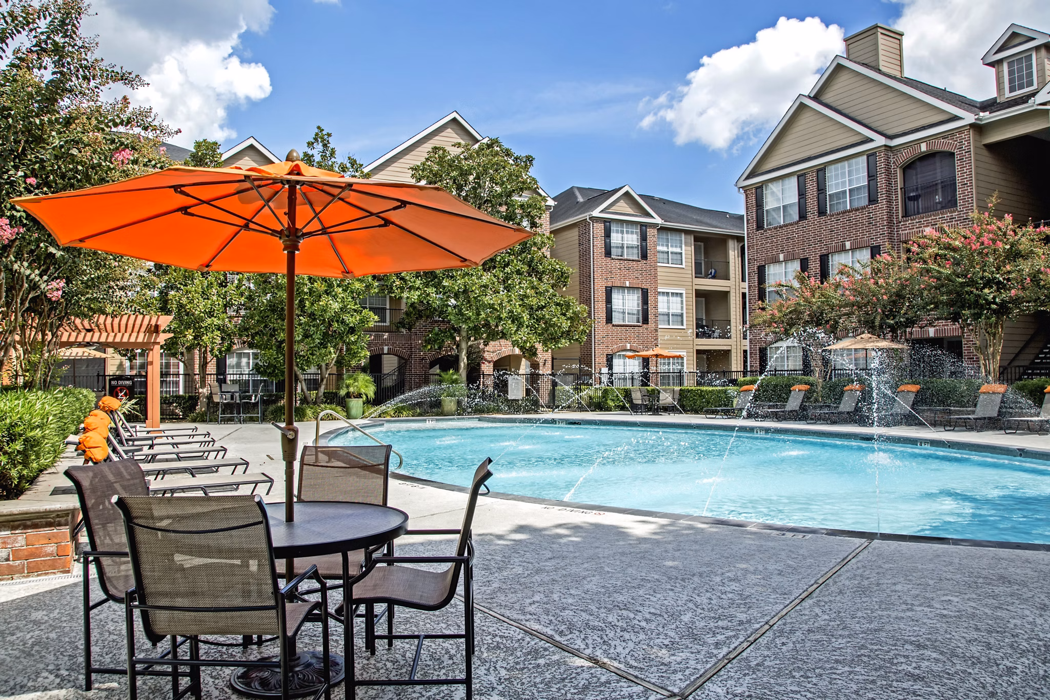 Resort-style pool surrounded by lush palm trees at Plaza at Westchase Apartments in the vibrant heart of Houston