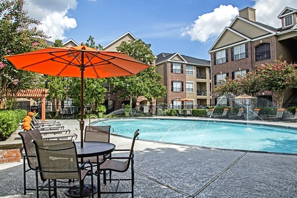 Resort-style pool surrounded by lush palm trees at Plaza at Westchase Apartments in the vibrant heart of Houston