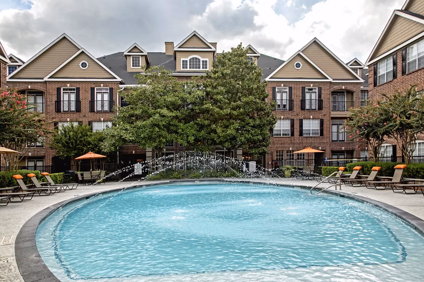 Resort-style pool at Plaza at Westchase Apartments featuring lush landscaping and lounge chairs