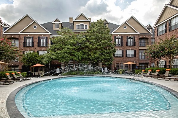 Resort-style pool at Plaza at Westchase Apartments featuring lush landscaping and lounge chairs