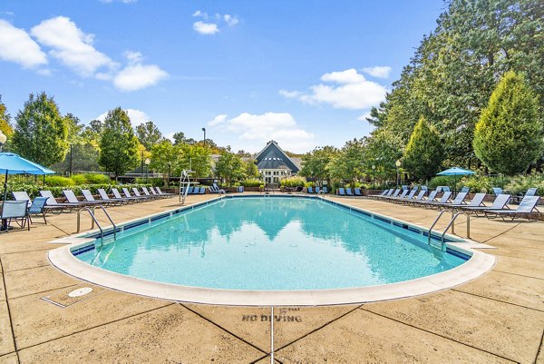 Pool with lounge chairs and umbrellas at Ellipse at Fairfax Corner Apartments