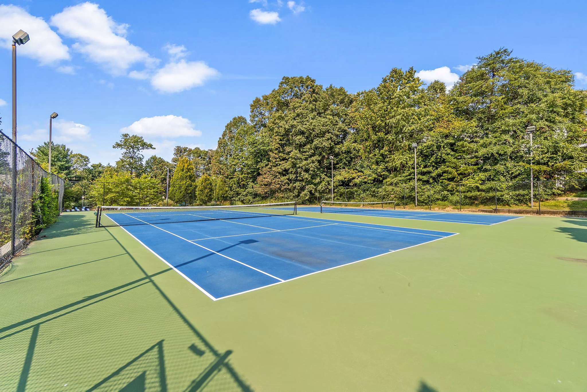Tennis court at Ellipse at Fairfax Corner Apartments with night lighting and seating area