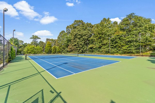 Tennis court at Ellipse at Fairfax Corner Apartments with night lighting and seating area
