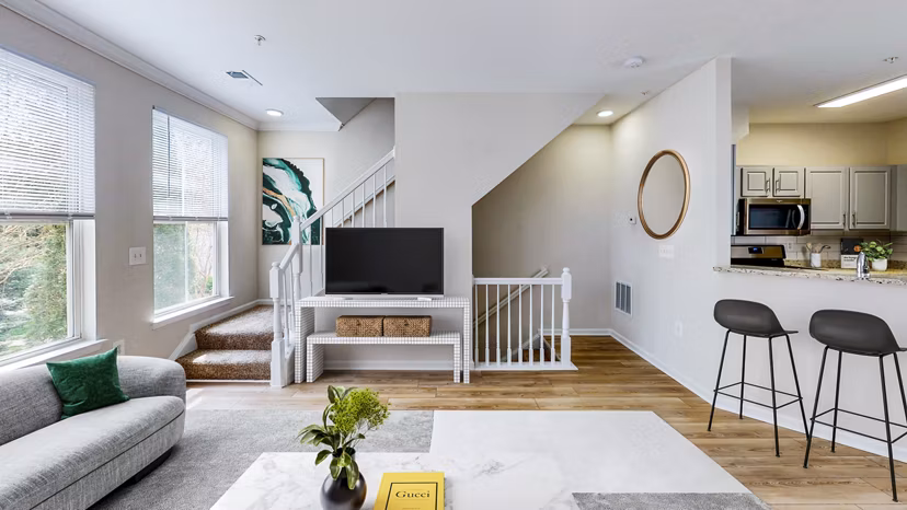Living room with cozy seating and large windows at Townes at Herndon Apartments
