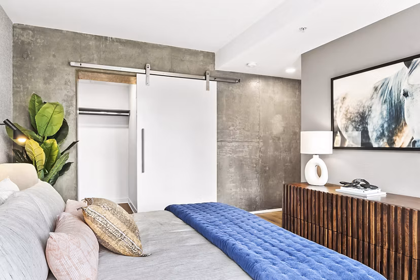 Cozy bedroom with modern decor at The Goodwin Apartments, featuring plush bedding and ample natural light for a luxurious living experience